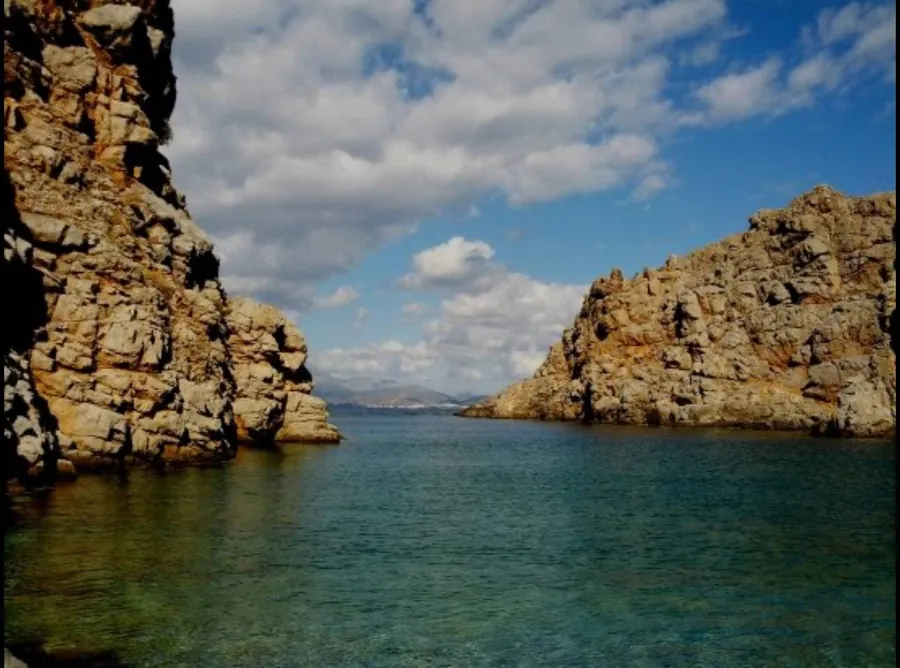 Small secluded cove surrounded by rocks with clear blue water at Agriomandra Beach